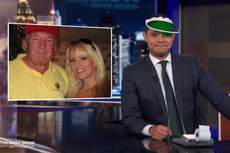 Trevor Noah, wearing an accountant's green eyeshade, in front of a picture of Trump and Stormy Daniels.
